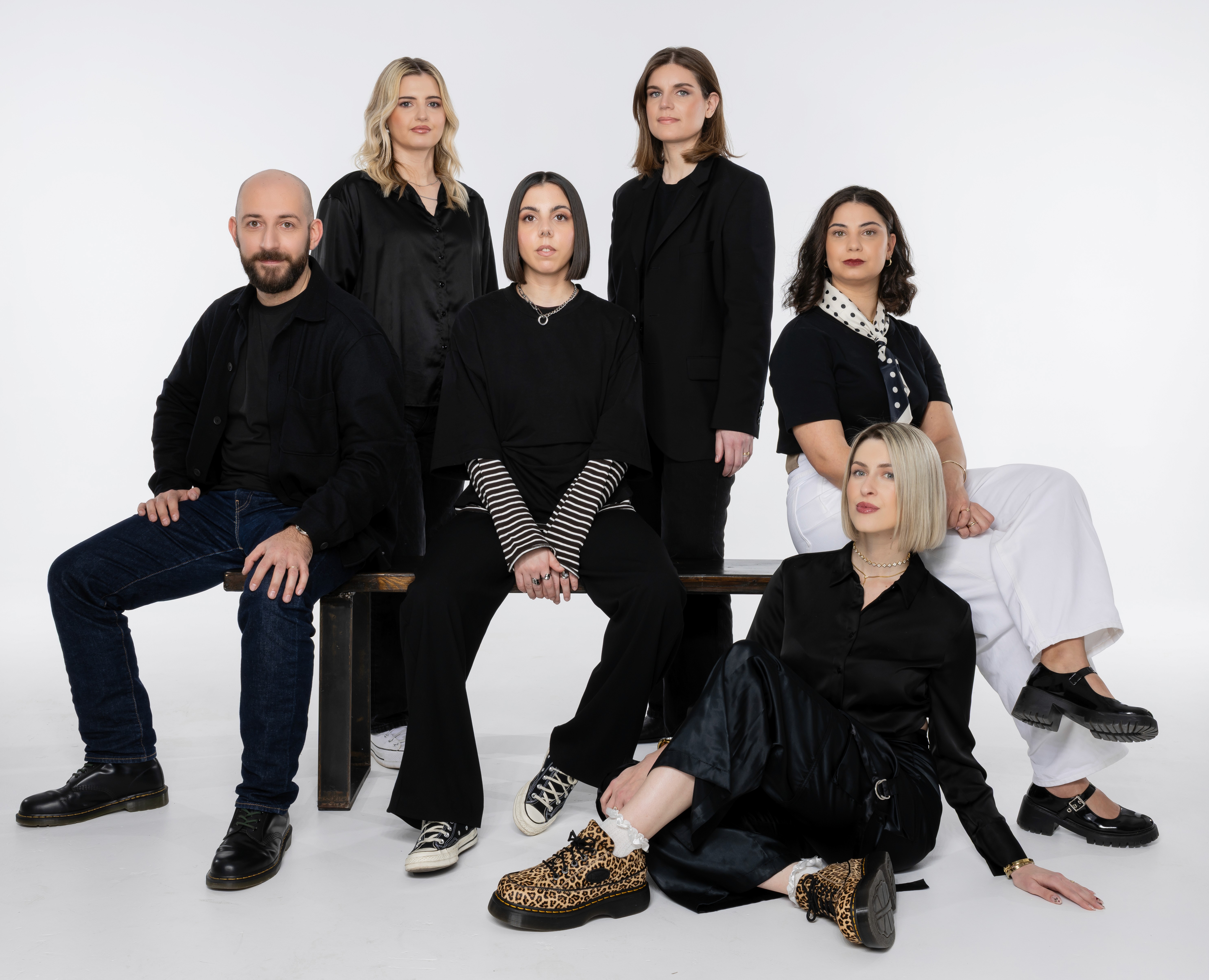 A large group photo of diverse team members gathered in an industrial-style space with arched ceiling.
