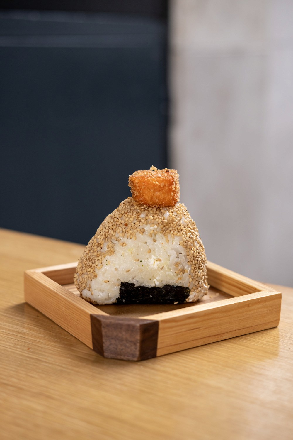 Wooden outdoor table set with multiple plates of food, including dips, salads, potatoes with cheese, and glasses of water, with hands reaching in to eat.