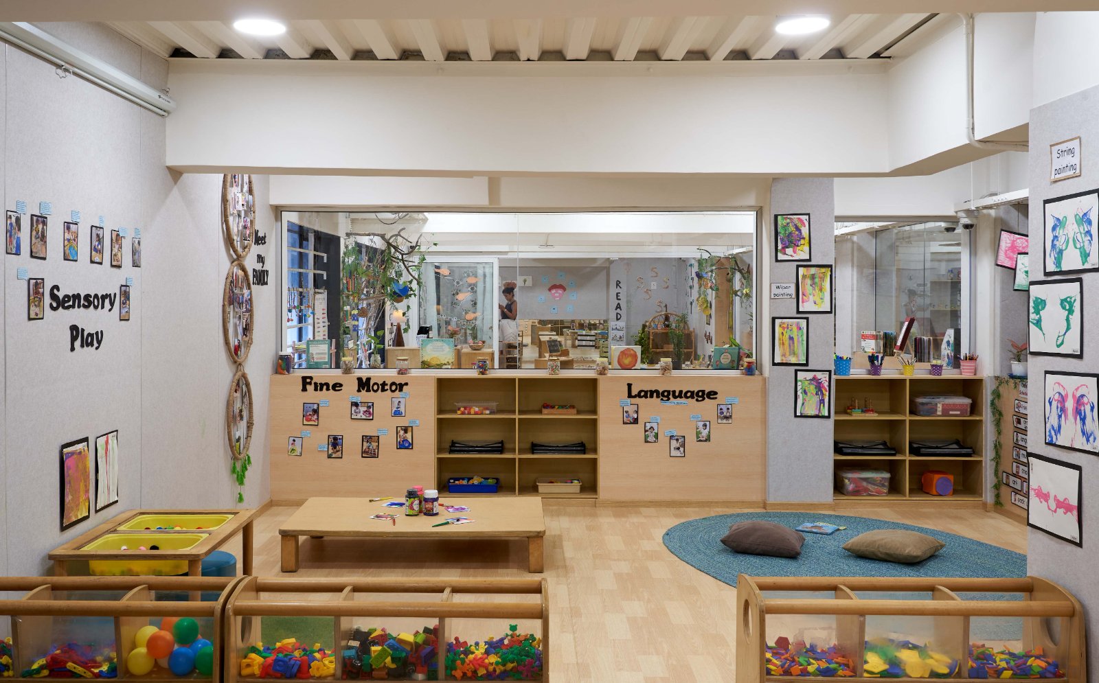 Nature-inspired preschool entrance with sculptural tree partitions and suspended green leaf ceiling panels.