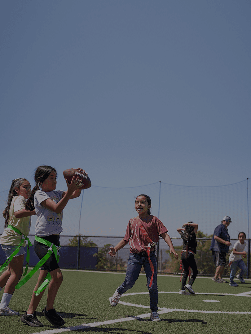 students playing flag football during a HOKALI after-school sports program on a school field