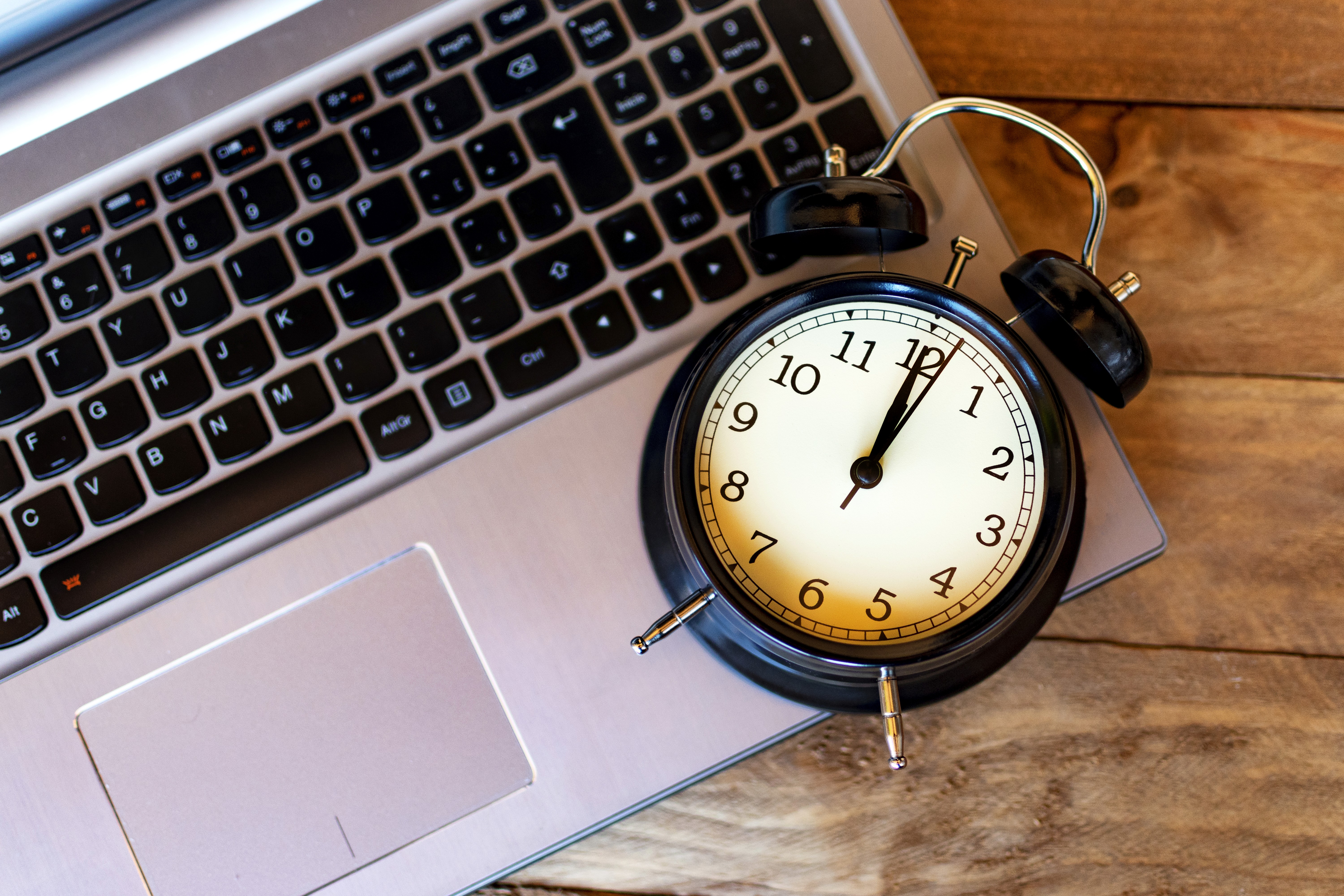 Alarm clock placed on a laptop keyboard symbolizing the importance of time in digital work and online performance