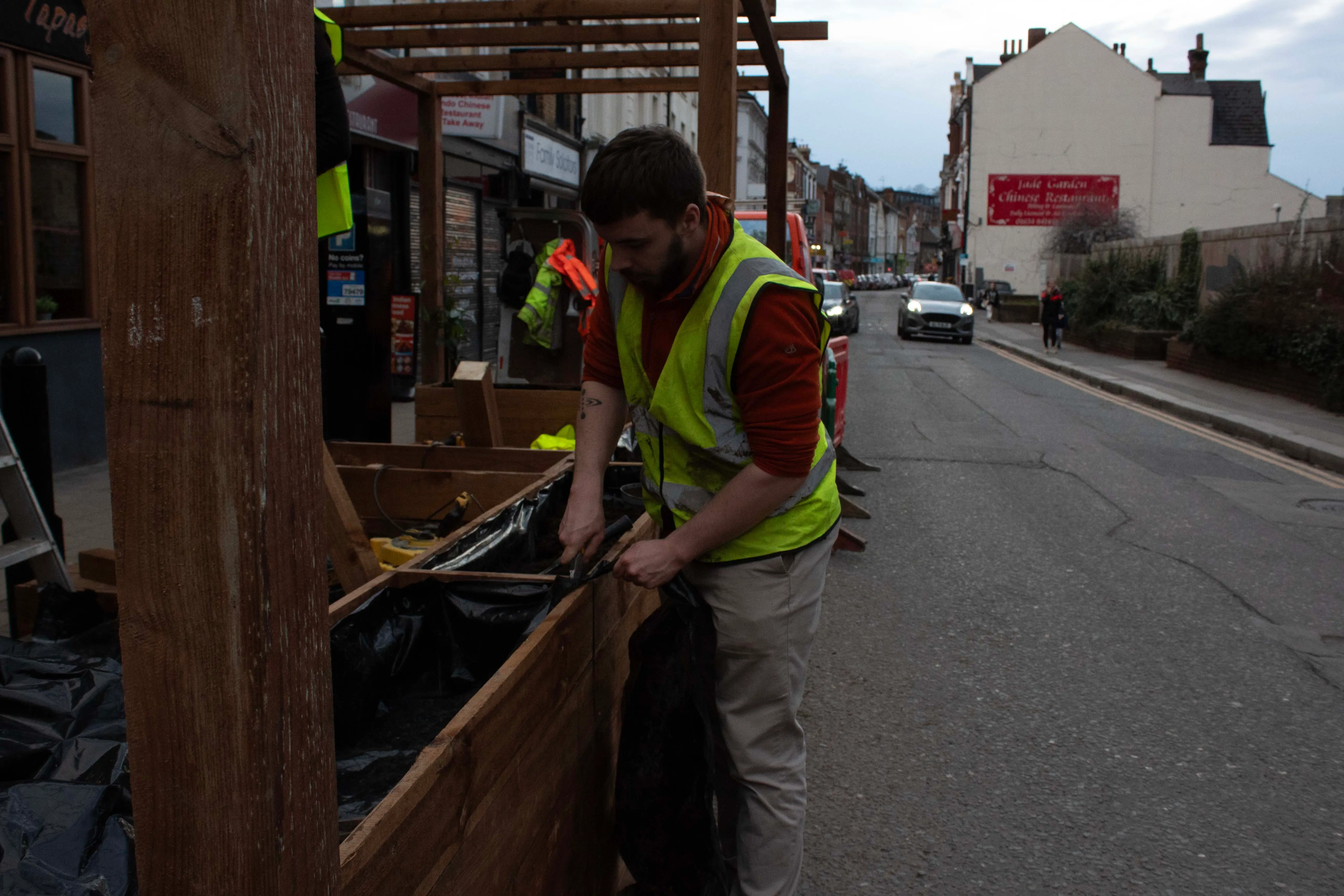 A worker in a safety vest is sorting items at a waste collection station on a street.