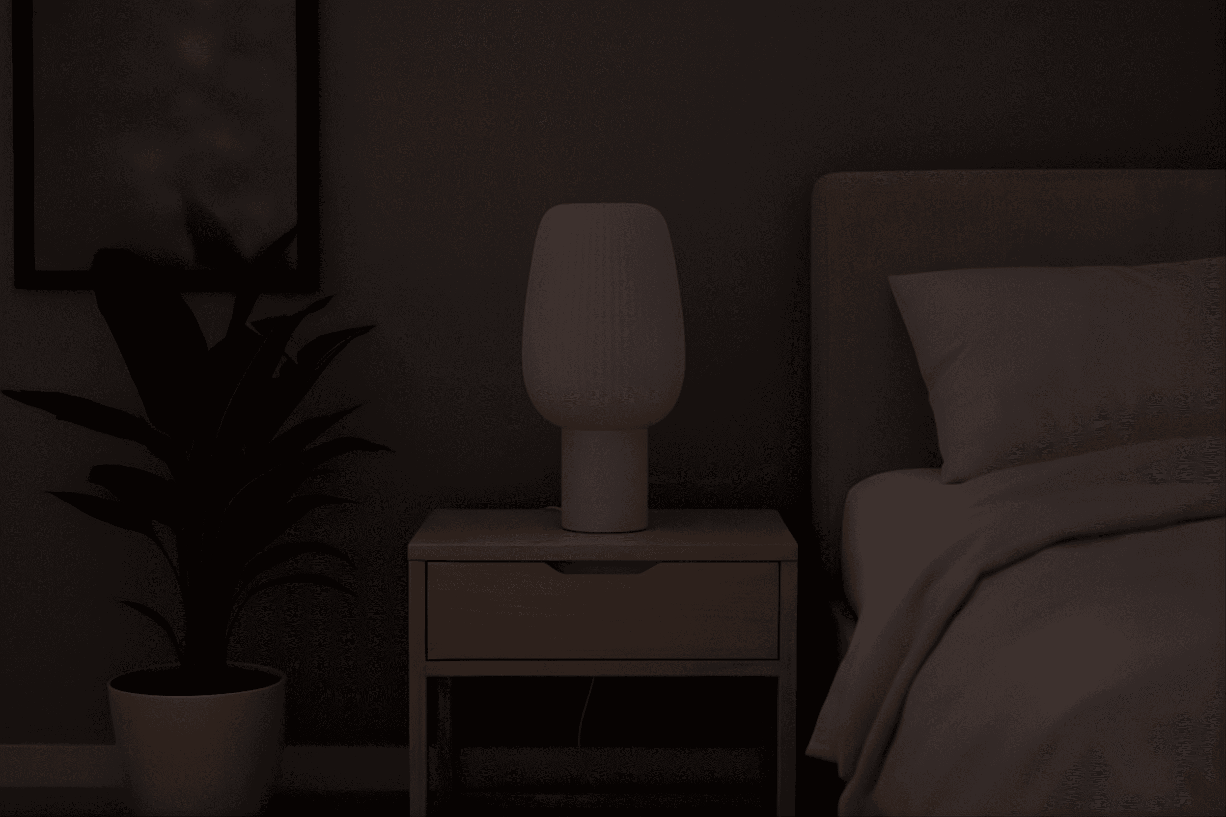 A warm, glowing table lamp with a ribbed glass shade sits on a light wood nightstand next to a bed. A potted plant stands to the left against a muted wall in a cozy, dim bedroom.
