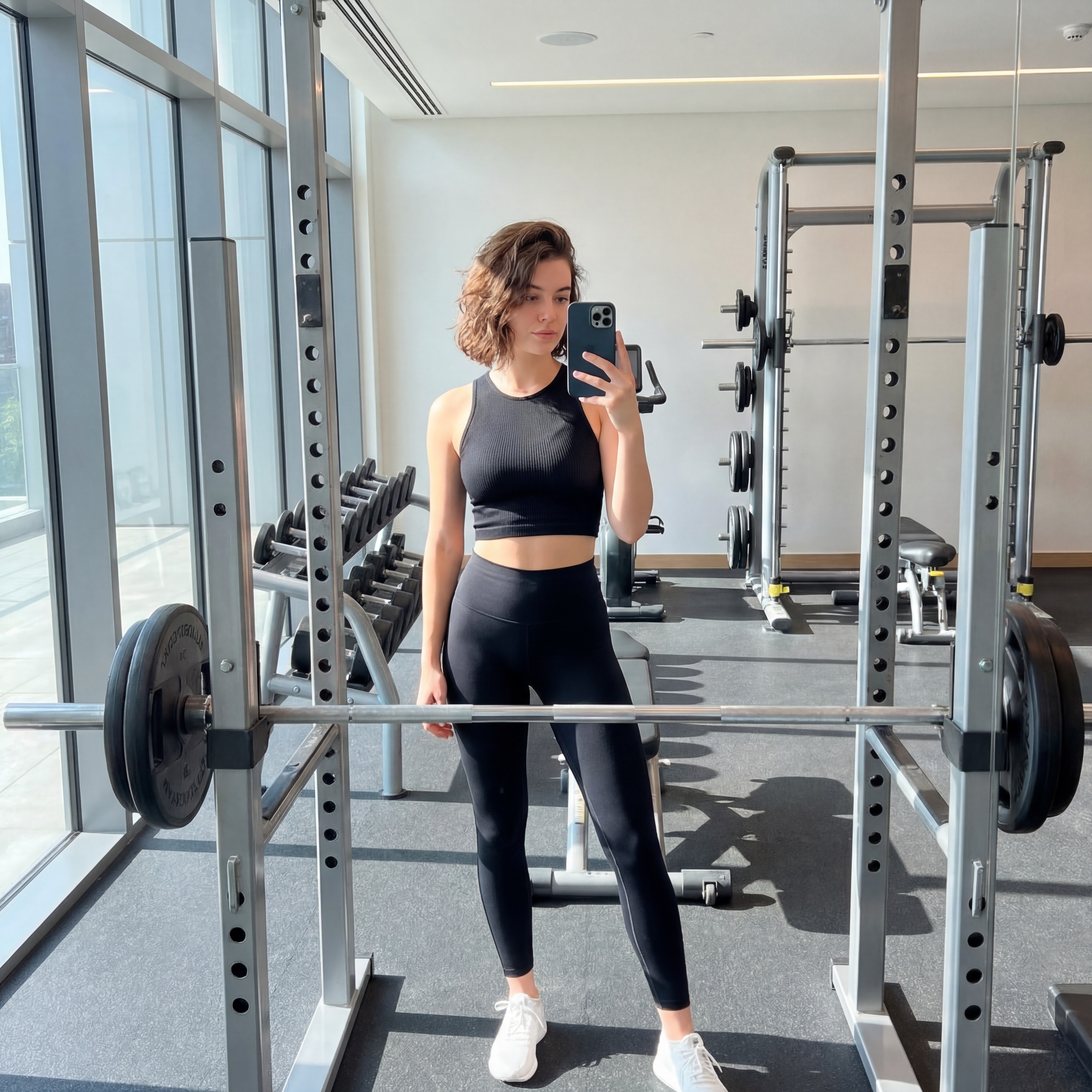 AI influencer fitness image generated using Nano Banana Pro AI image generator, realistic gym mirror selfie with black athletic wear and natural daylight, tested for realism in latest AI image generator comparison like GPT Image 1.5 and Seedream 4.5.