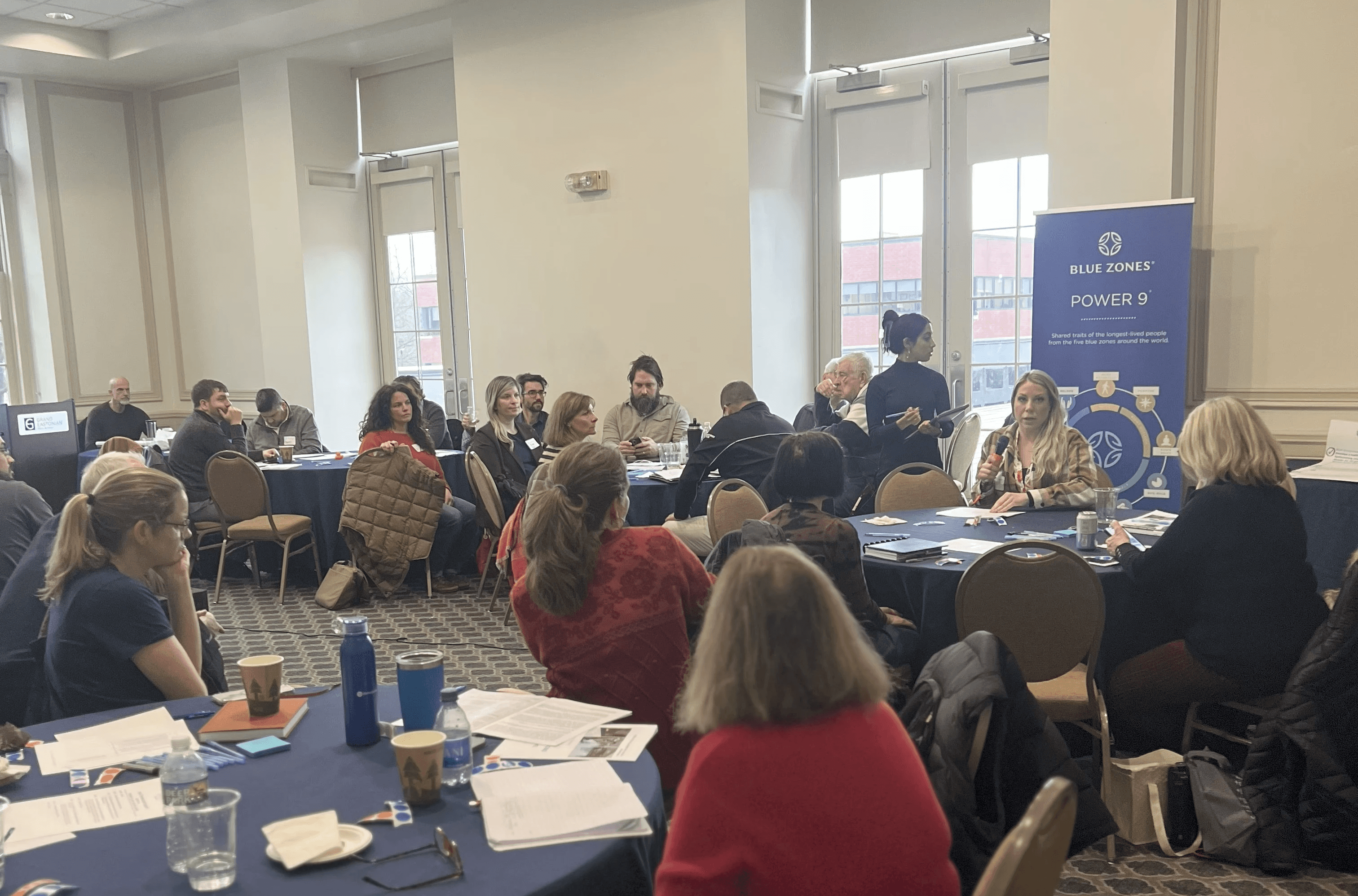 Modern home office setup with a monitor, ergonomic chair, keyboard, and indoor plants near a window with blinds.
