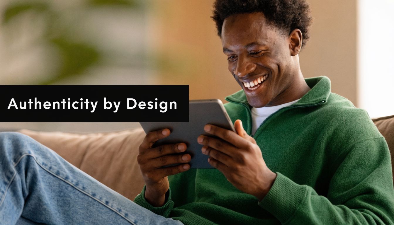 A happy young man wearing a green sweater using a digital tablet while sitting on a sofa.