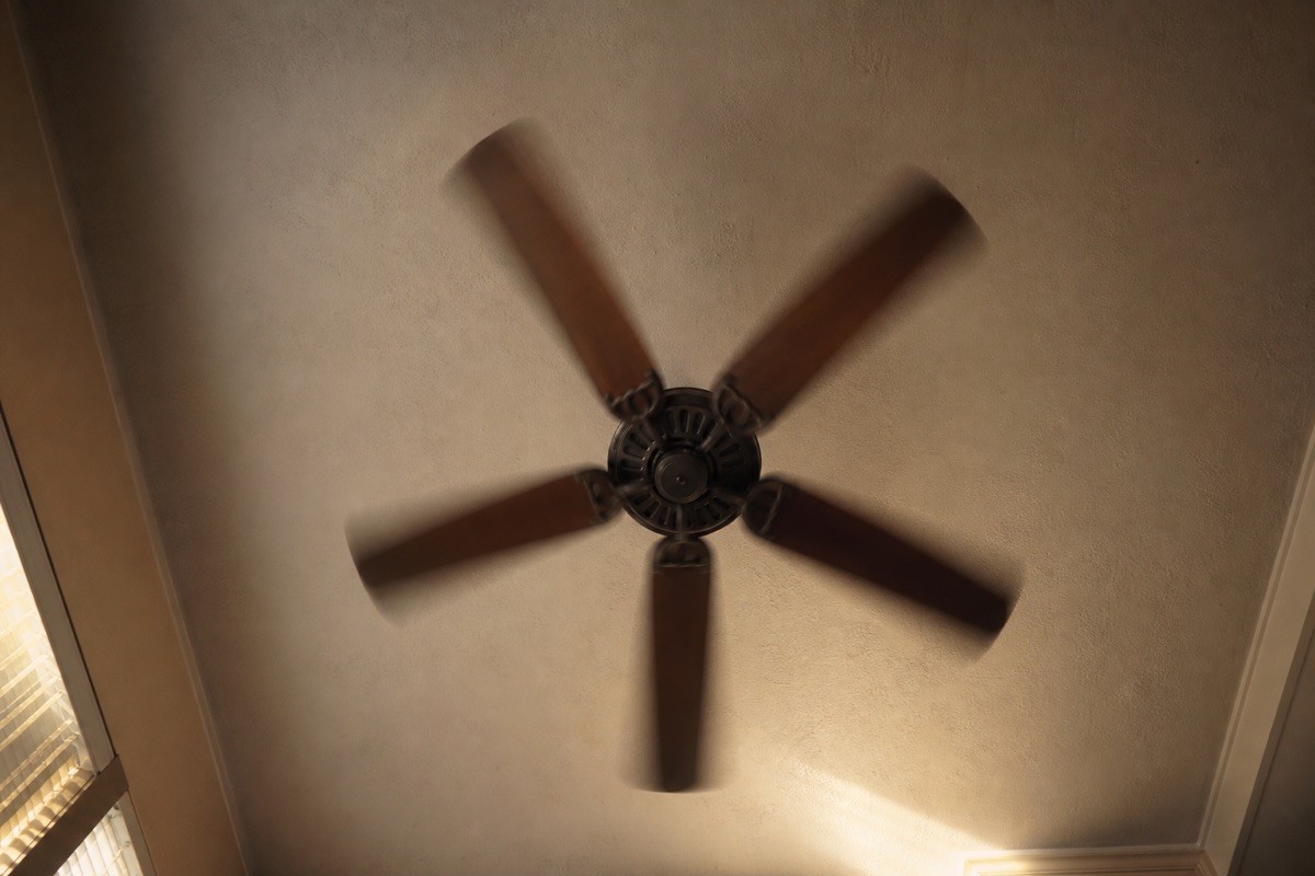 A dramatic upward view of a ceiling fan moving air across the whole room