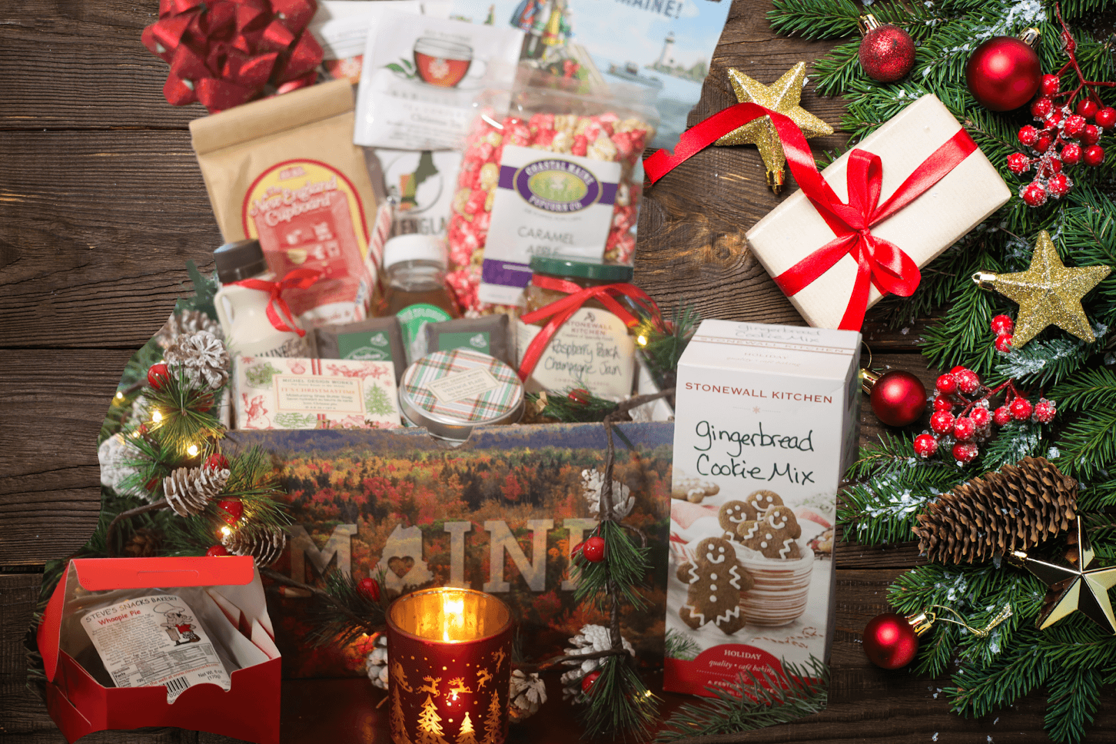 A festive gift box featuring a candle, cookies, and assorted Maine-made items, embodying the spirit of the holiday season.