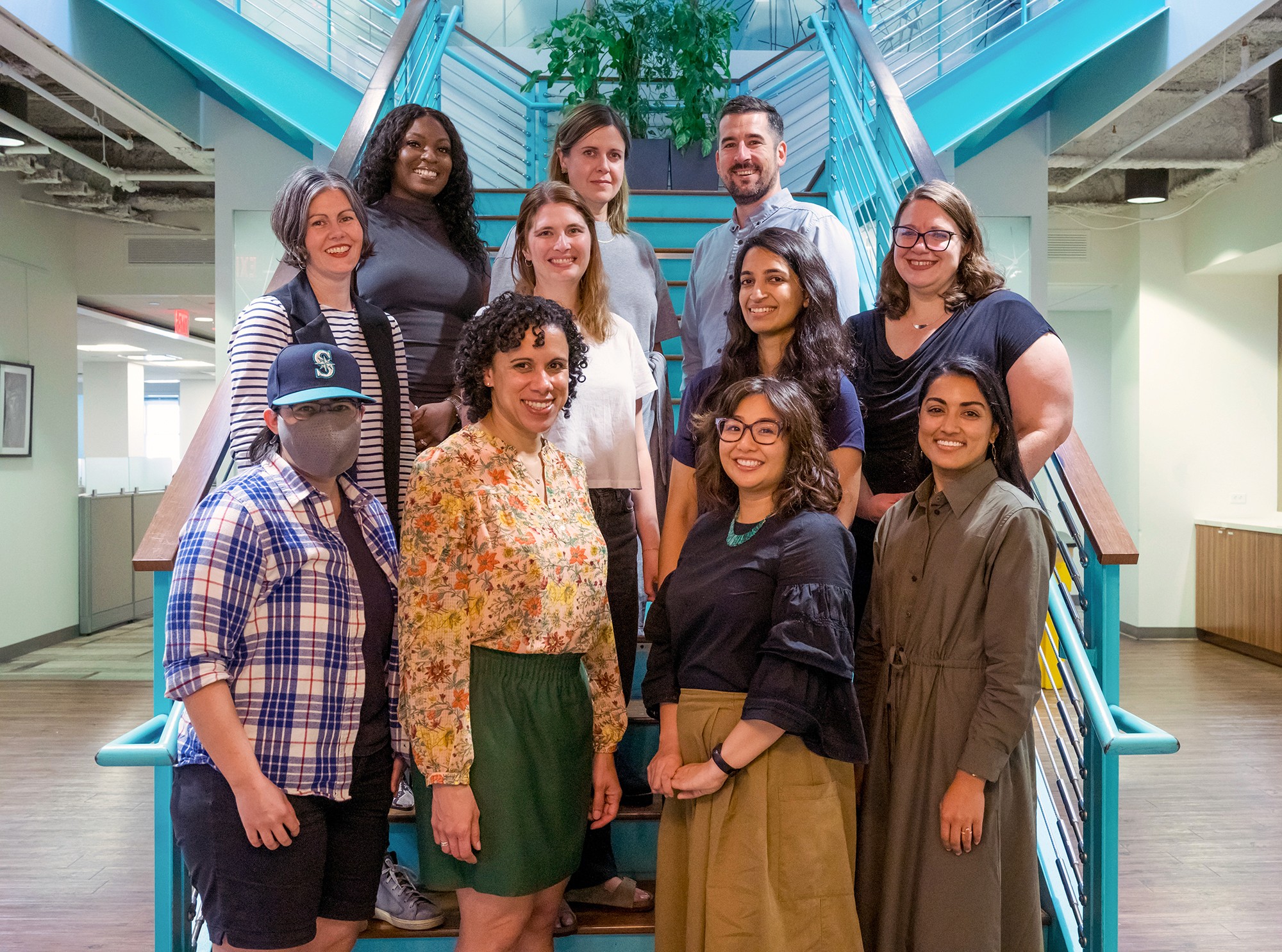 The New Practice Lab team standing in a group portrait staged in a stairway of a modern office. 