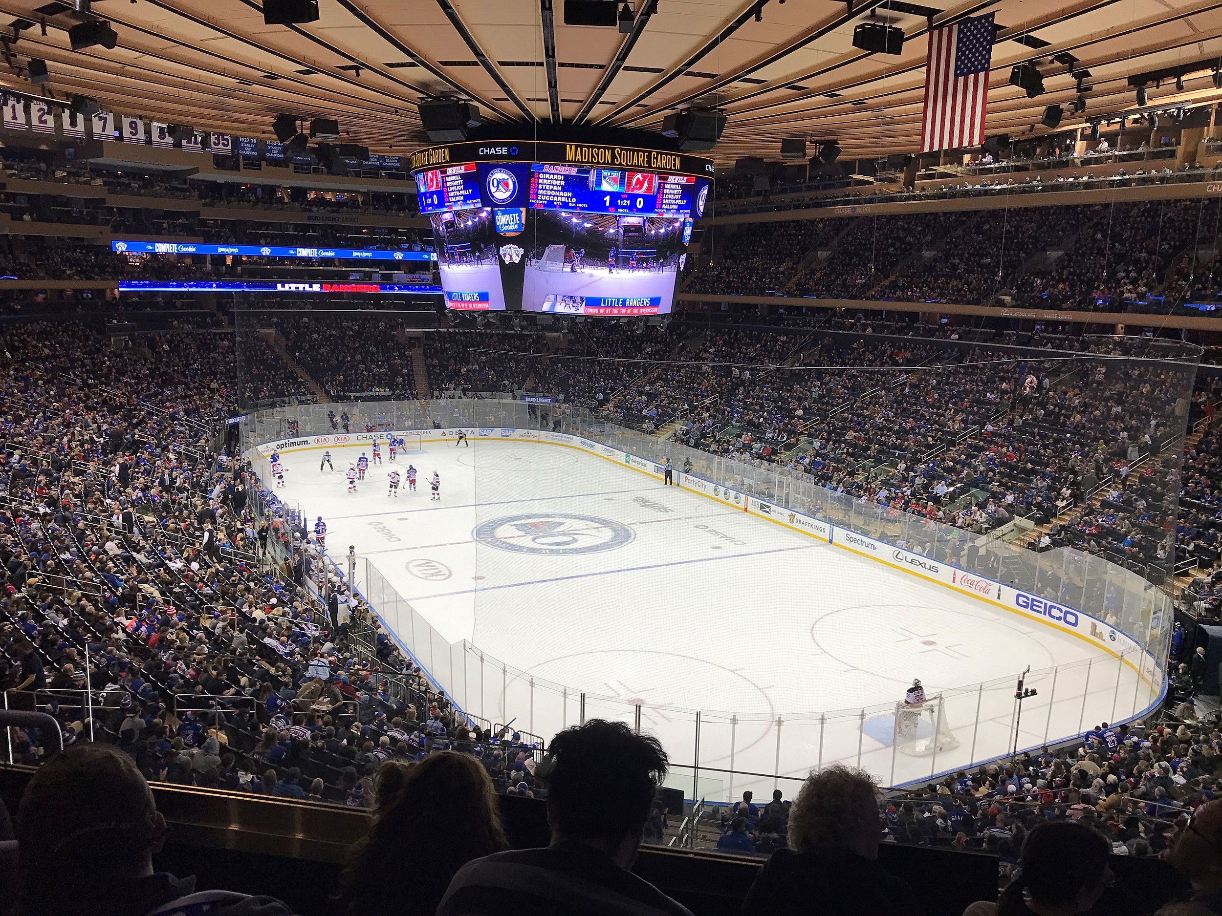 Madison Square Garden interior with the ice illuminated and the jumbotron displaying the New York Rangers logo before a hockey game.