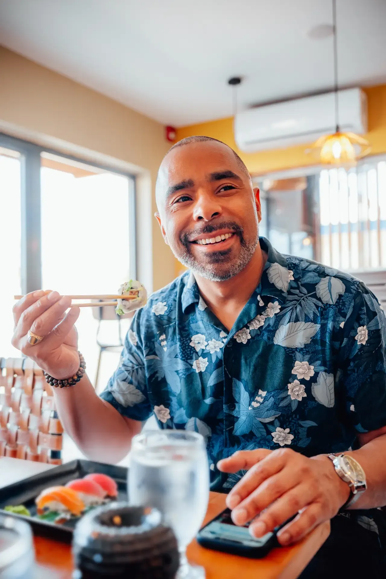 Guest smiling and raising a vibrant fruit cocktail in celebration at Nikkei Aruba