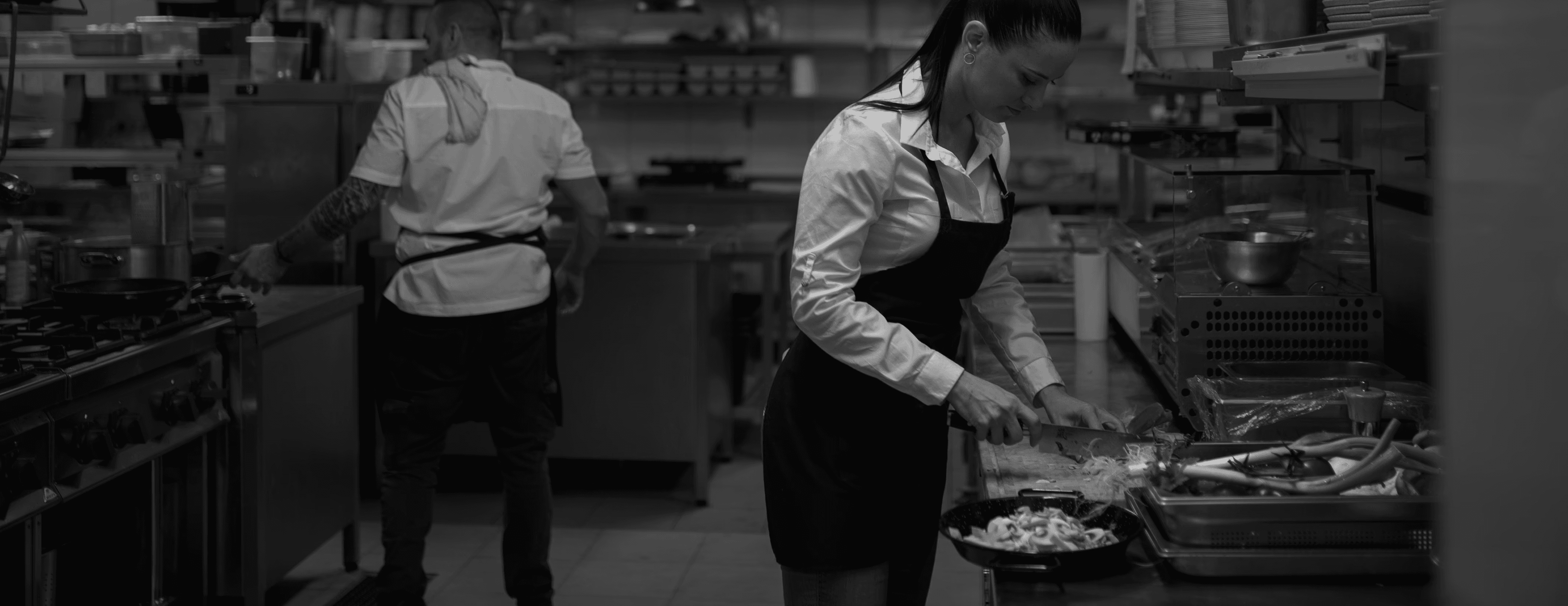 White plate with roasted chicken served in a golden sauce with herbs and capers, placed on a terrazzo tabletop in sunlight.