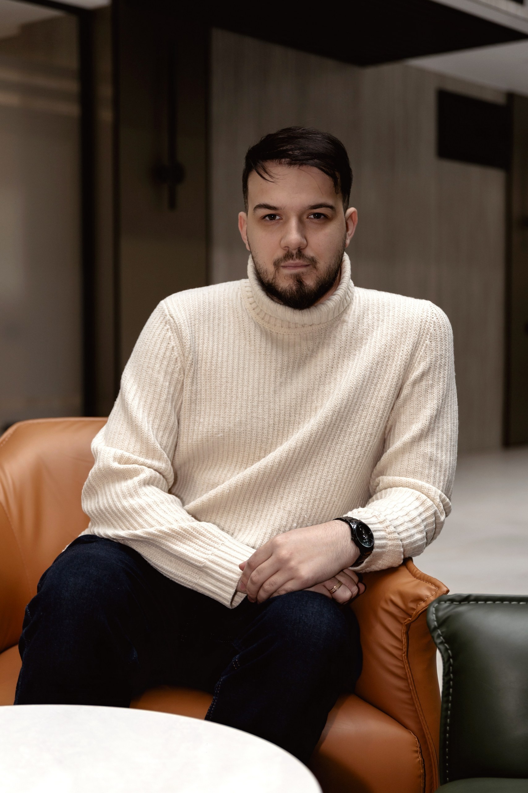 Minimal studio portrait of a confident woman in a white shirt, arms crossed, on a soft gray background.