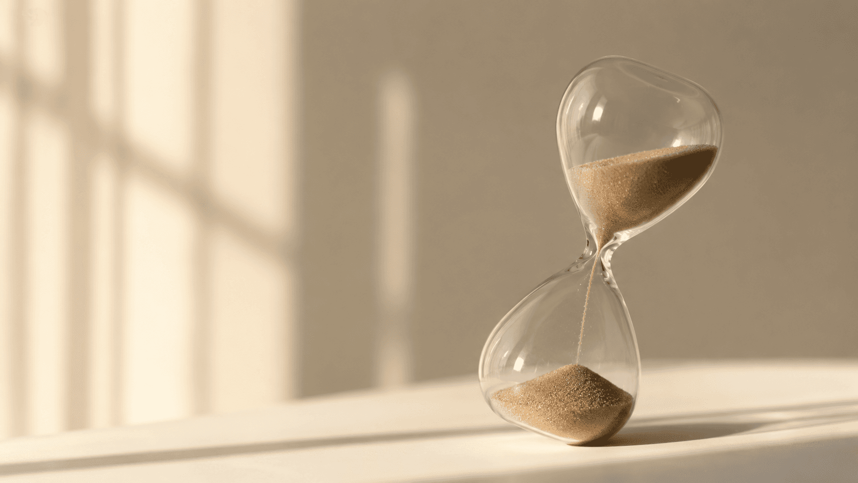 Hourglass on desk showing time and money lost during slow hiring process