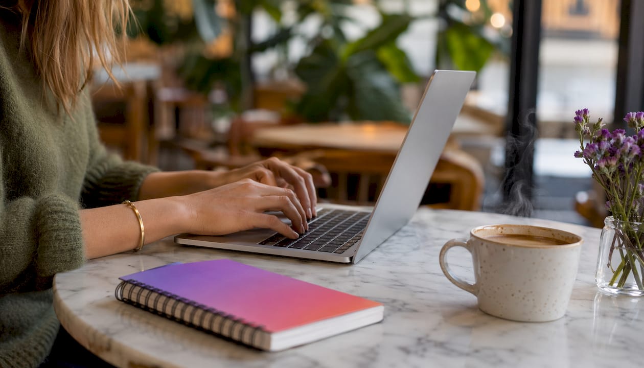 Hands typing on laptop in home office