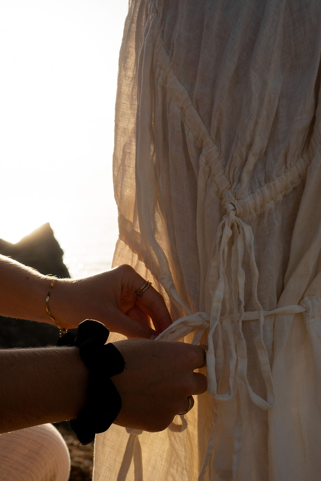 Close up of hands adjusting a bow at a white dress
