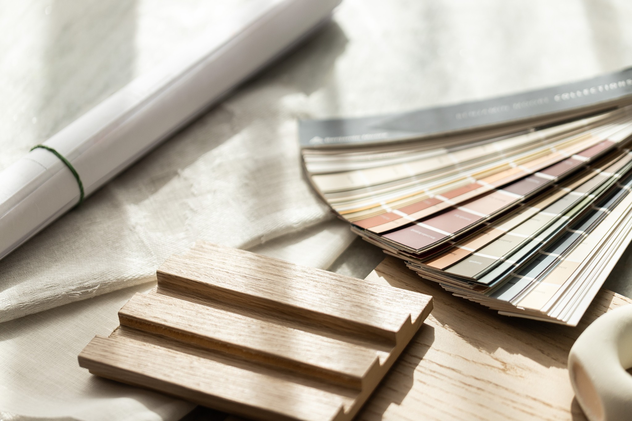 Wooden flooring samples and color swatches with rolled documents displayed on table.