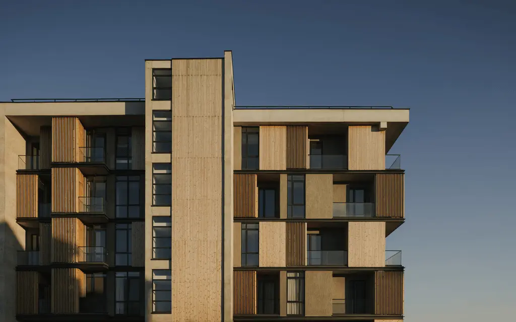 Modern residential building facade with wooden panels and balconies at sunset