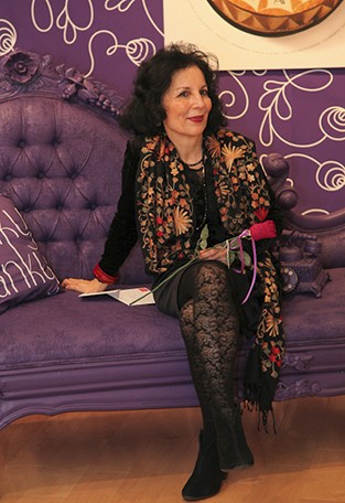 a photo of an older woman sitting on a purple couch
