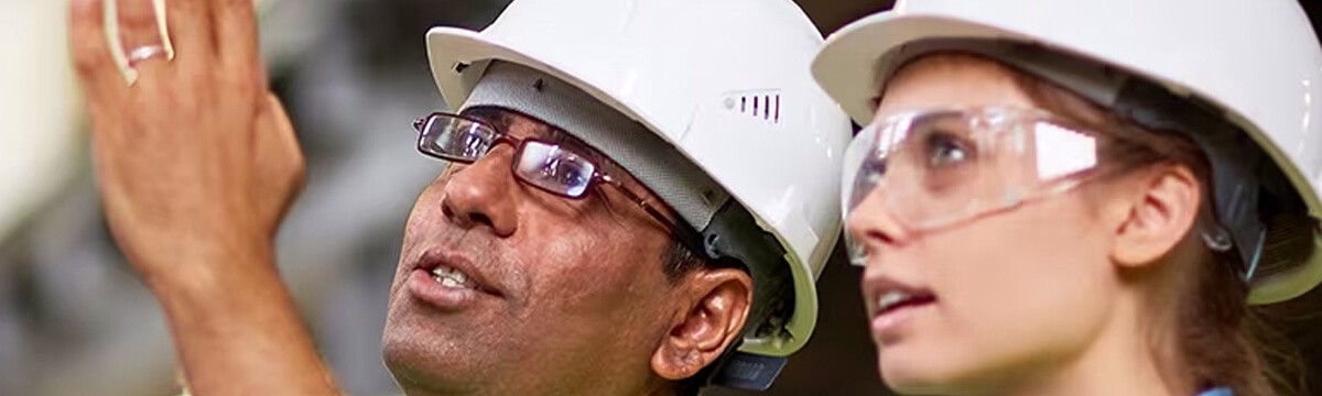 Two design professionals wearing hard hats discussing construction.