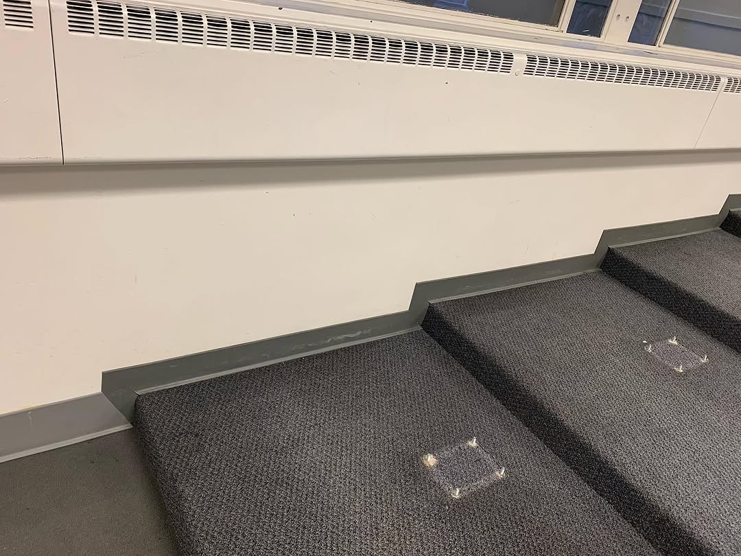 Worn grey carpet on tiered conference room risers before removal