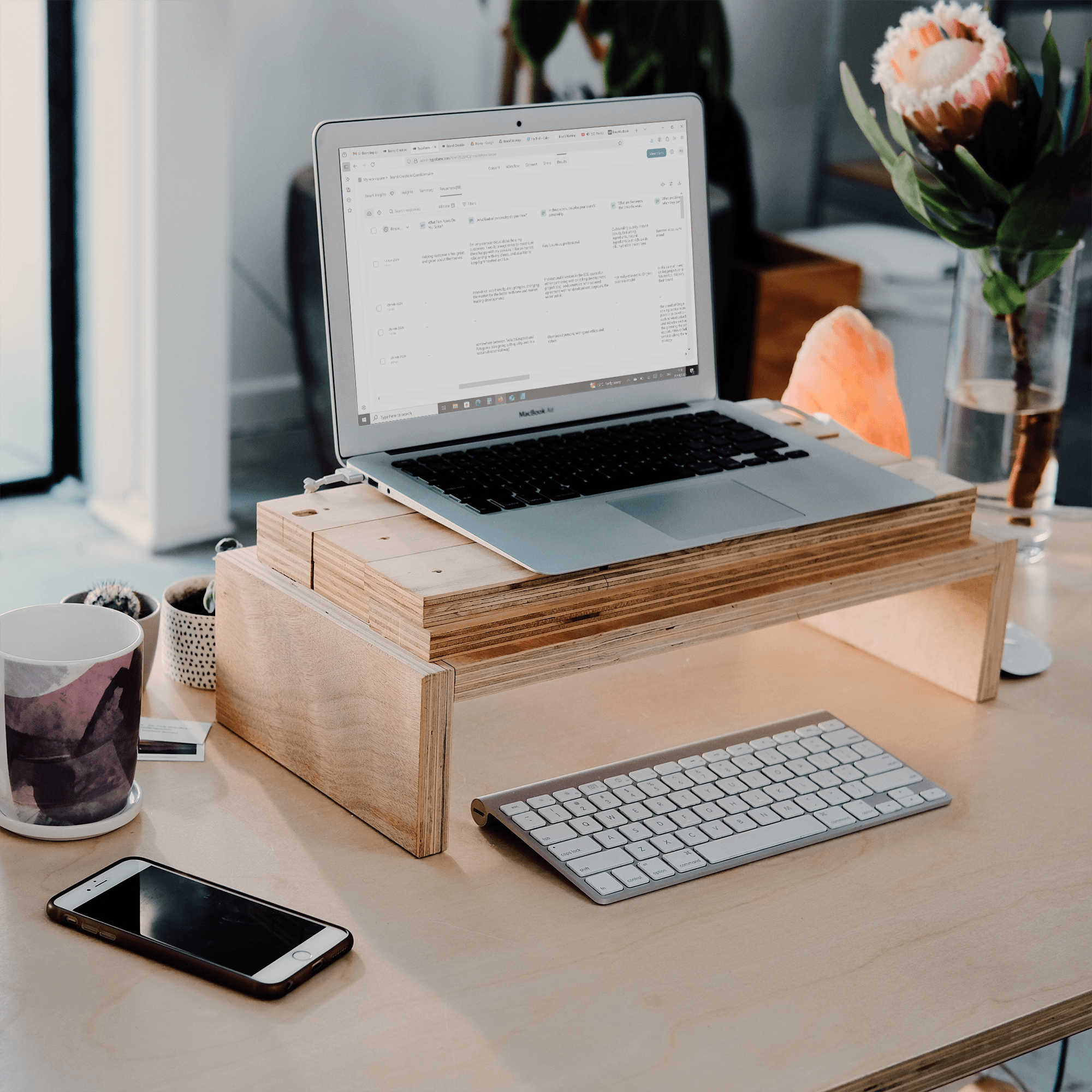 Wooden desk setup with laptop, notebook, and workspace items.