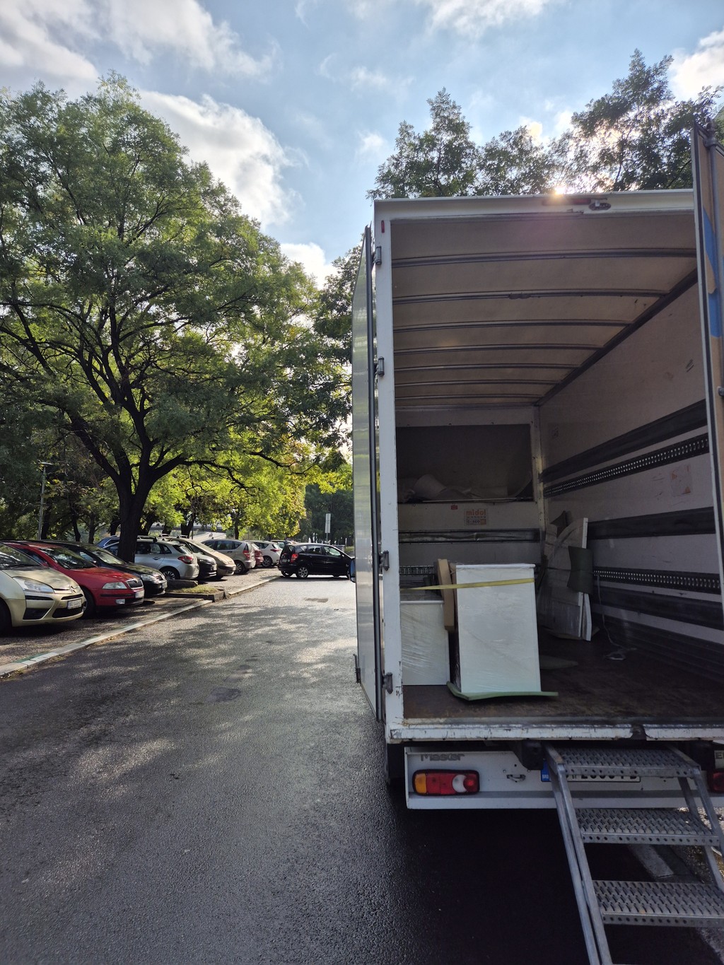 Kamion za selidbe parkiran na ulici tokom utovara nameštaja, uz rampe i uredno spakovane kutije, simbolizuje profesionalnu i bezbednu uslugu selidbi u Beogradu.