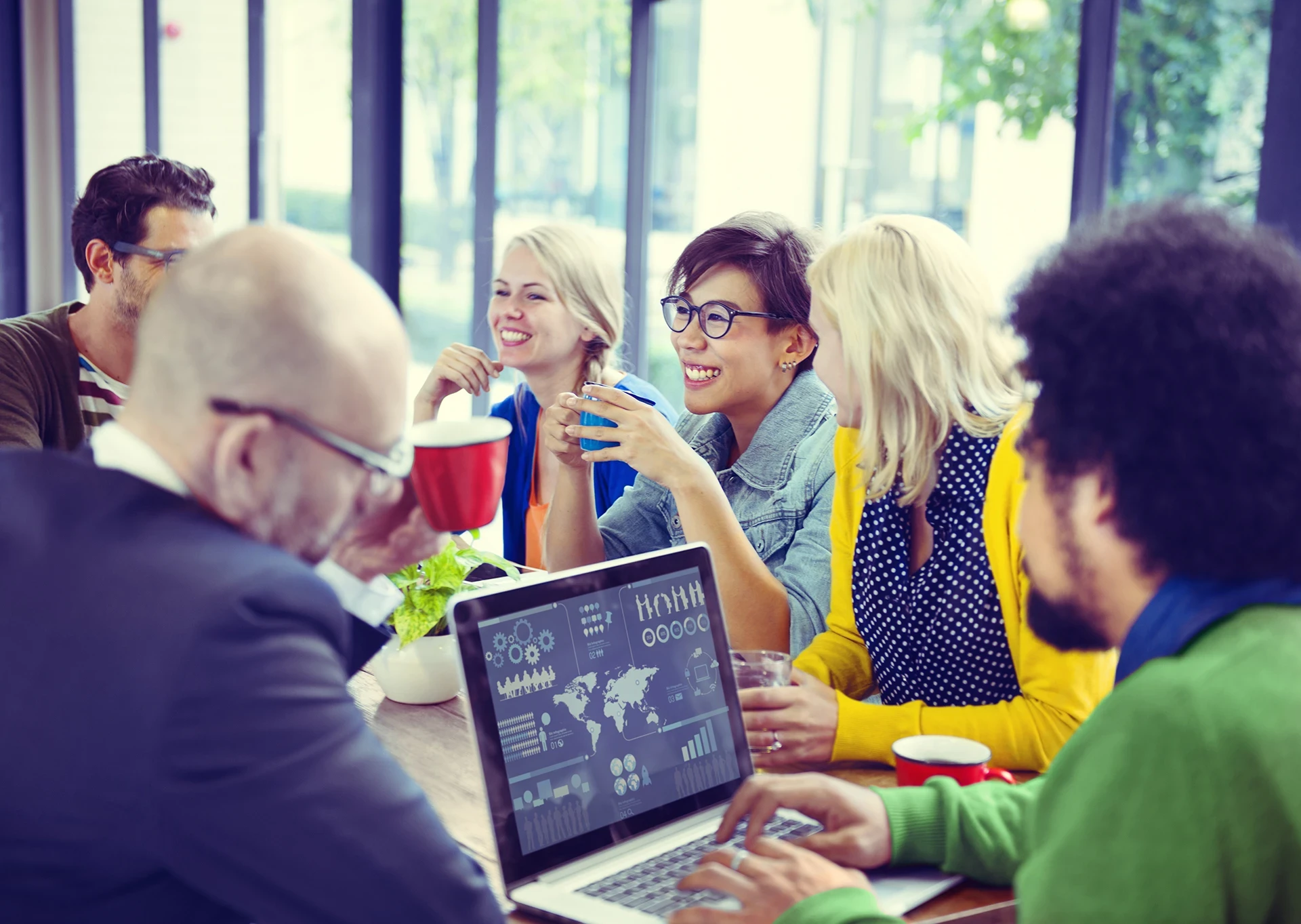 Marketing agency team collaborating around a laptop displaying data analytics and performance dashboards.