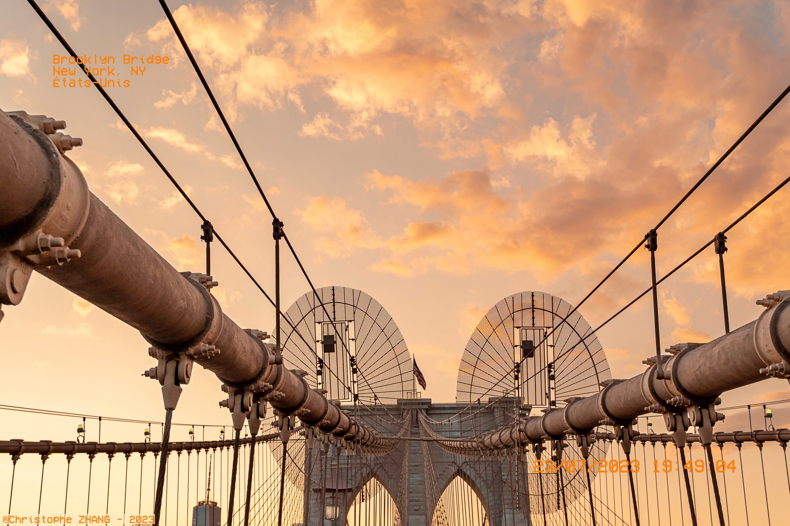Structure du Brooklyn Bridge au crépuscule, illuminée par les couleurs du ciel.