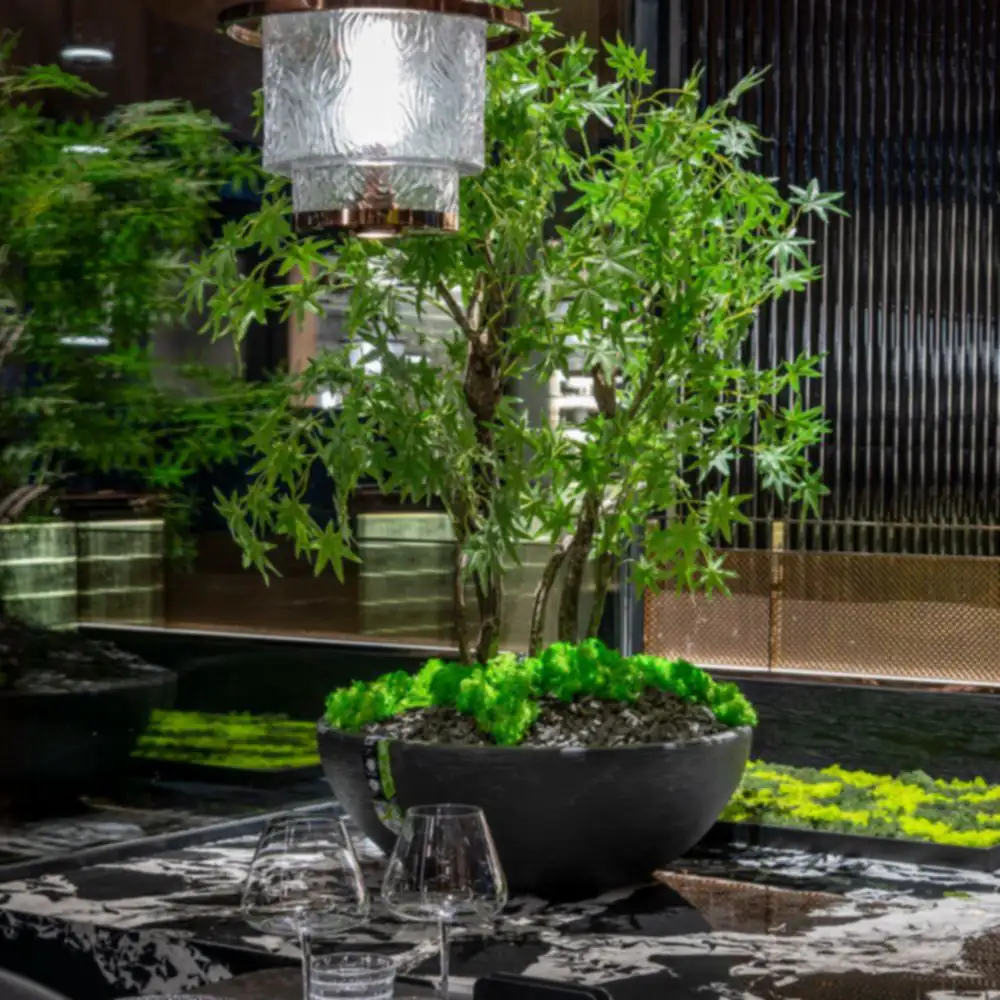 Lanterne de cristal au-dessus d’un jardin de table, devant un mur cannelé et des voiles de cuivre