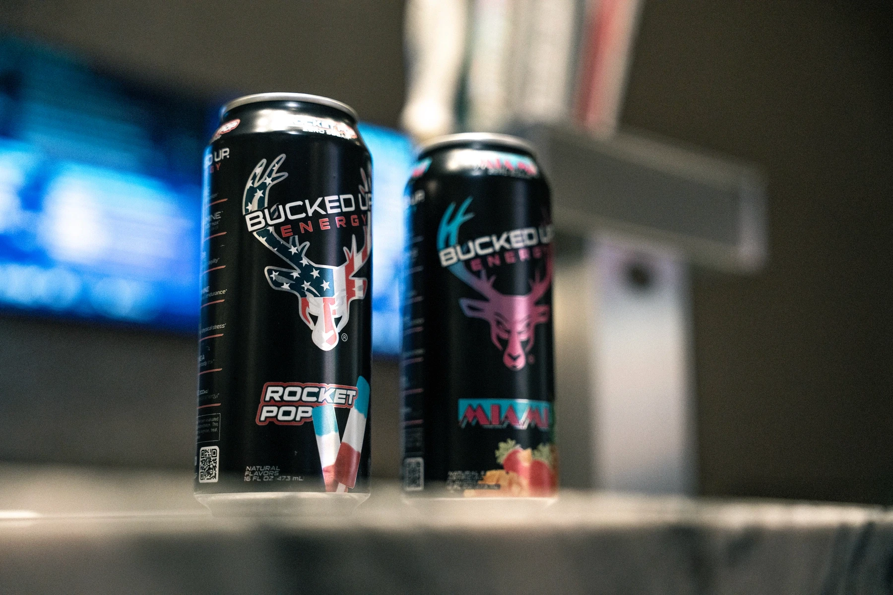 Close-up of two Bucked Up Energy drink cans on a countertop, featuring the Rocket Pop and Miami flavors with bold antler logos and vibrant label designs. The image captures the brand’s dynamic flavor lineup and colorful packaging.