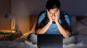A man looking at a screen in the dark