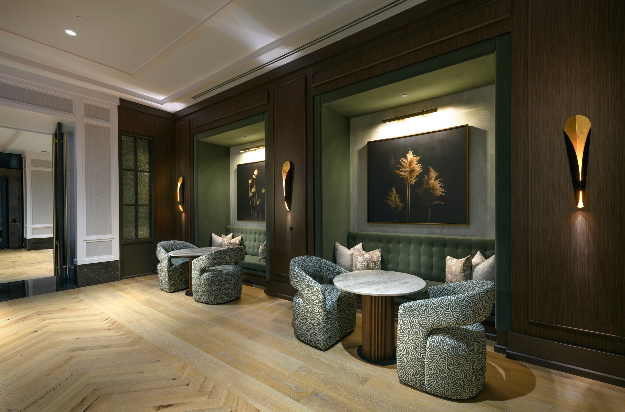 Waiting area with upholstered chairs, tables, and art.