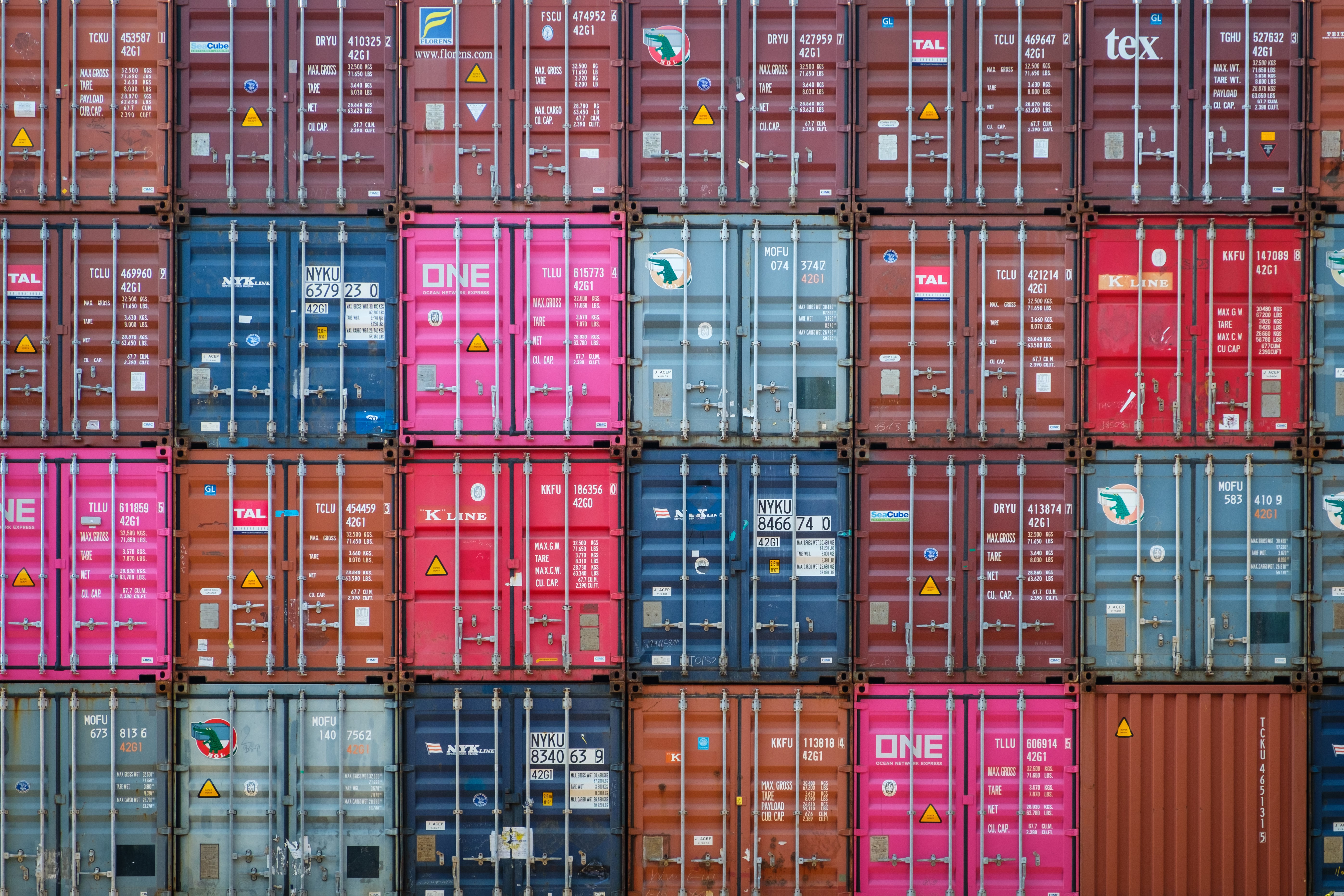 Des conteneurs maritimes de différentes couleurs empilés dans un terminal de fret.