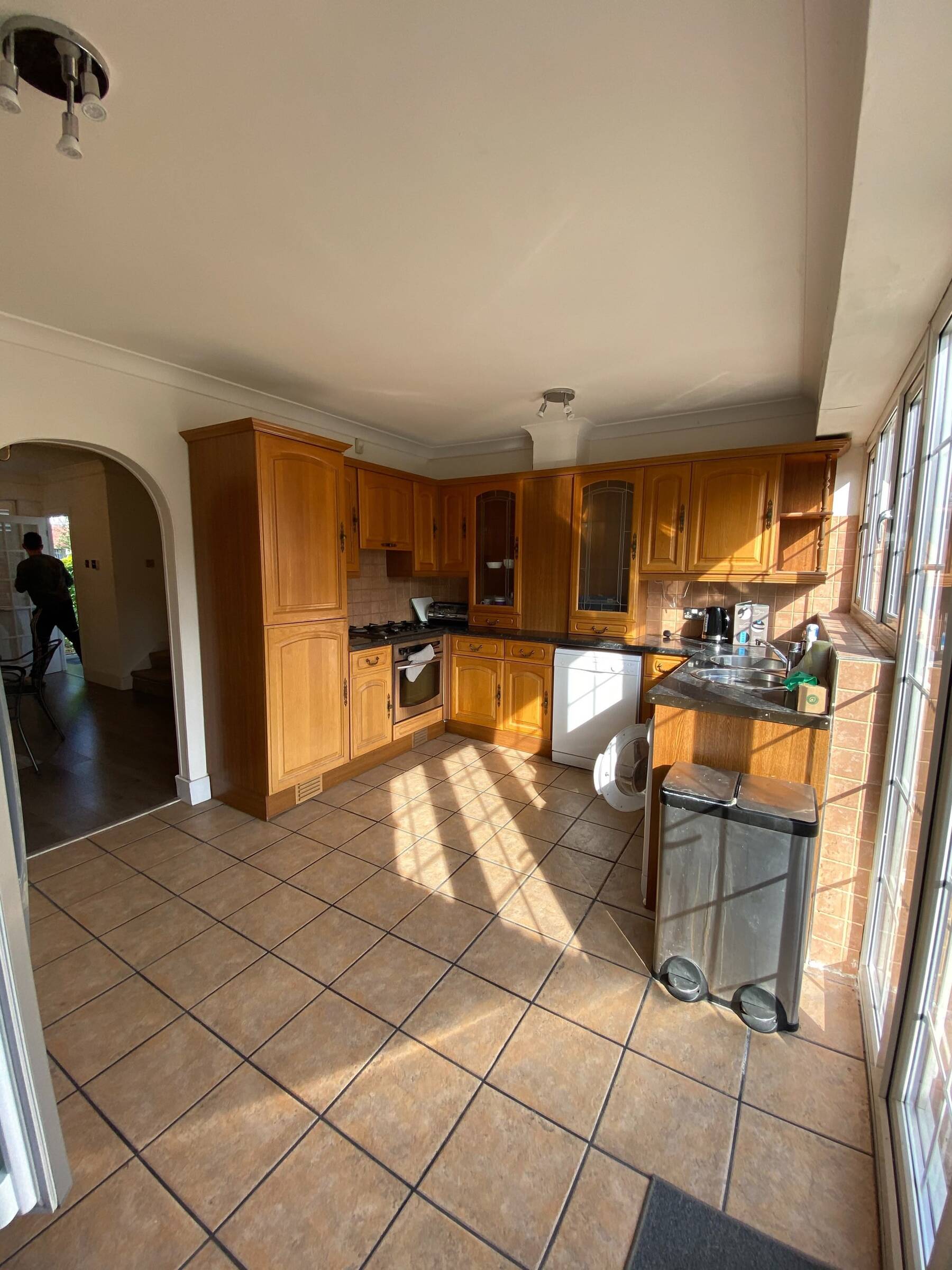 Kitchen before and after transformation by Atelier Akuko, updating dated cabinets, brass handles, and yellow tiles into a vibrant, modern space