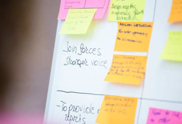 A whiteboard with handwritten notes and multiple colorful sticky notes, including one that says "Join forces, stronger voice.
