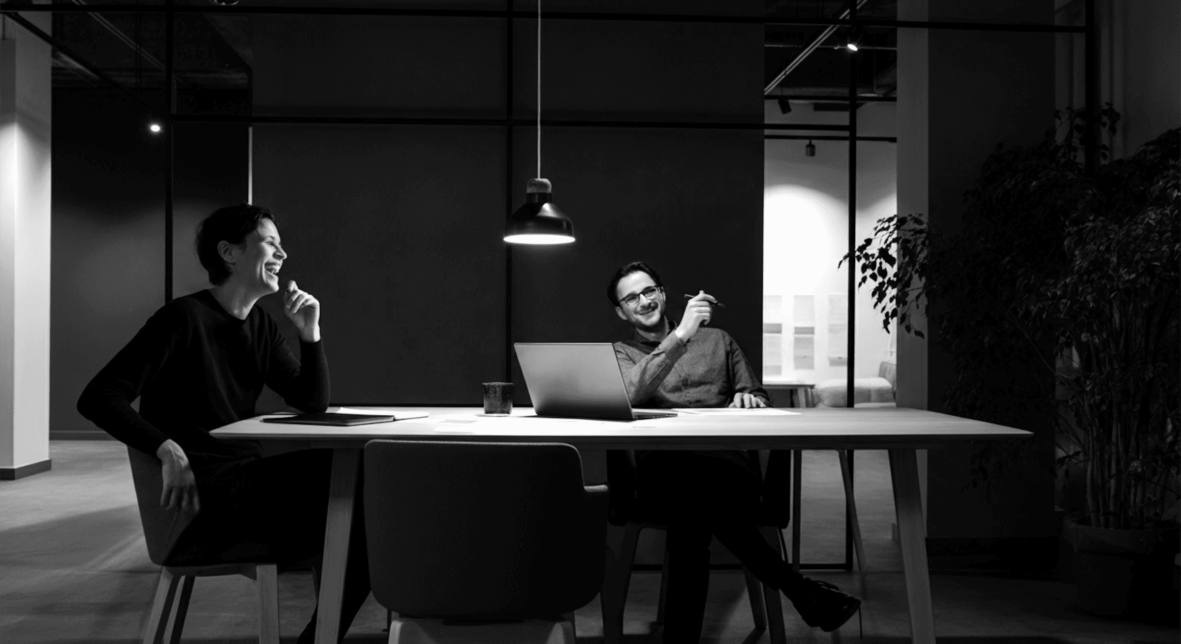 A man and a woman are sitting at a desk in an office.