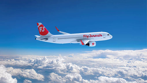 Three workers in safety gear and helmets are suspended by ropes, cleaning a modern building's slanted roof, against a clear blue sky.