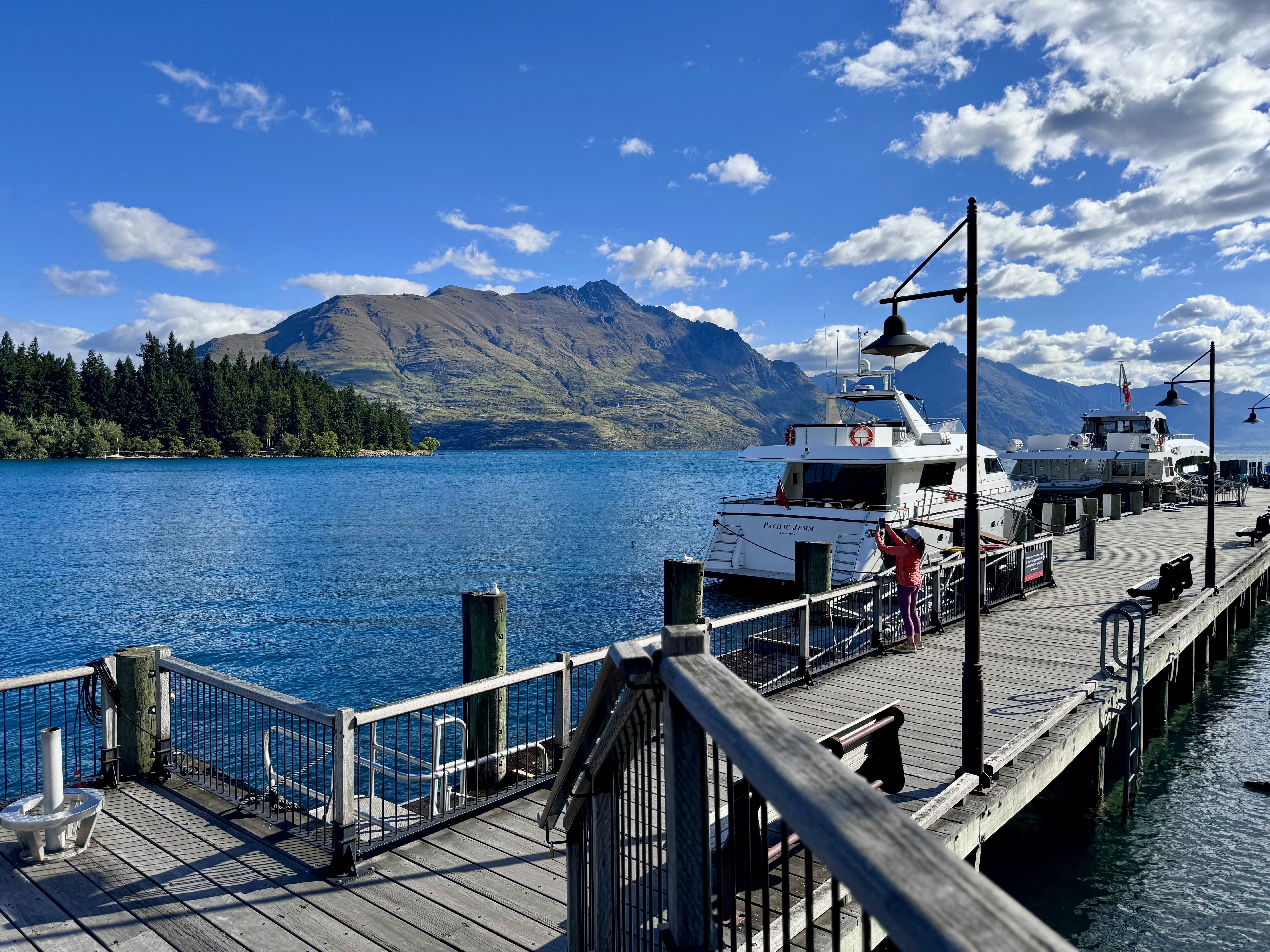 A beautiful view of lake Wakatipu, the Remarkables and a cruise boat by the pier.