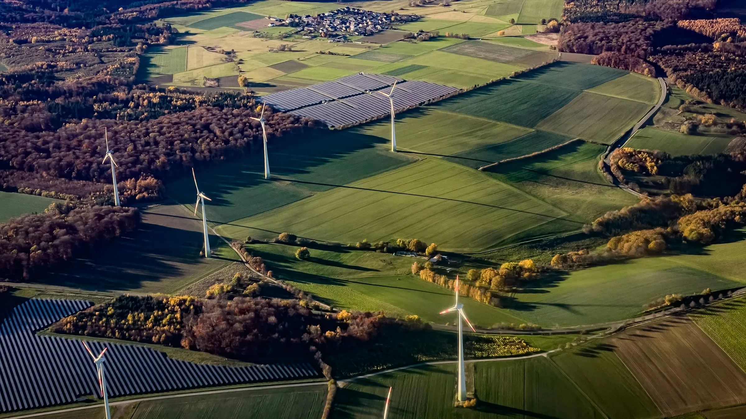 Aerial view of wind turbines and solar panels across rolling farmland