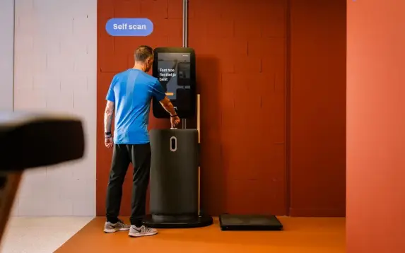 A person uses a treadmill in a gym surrounded by modern equipment.