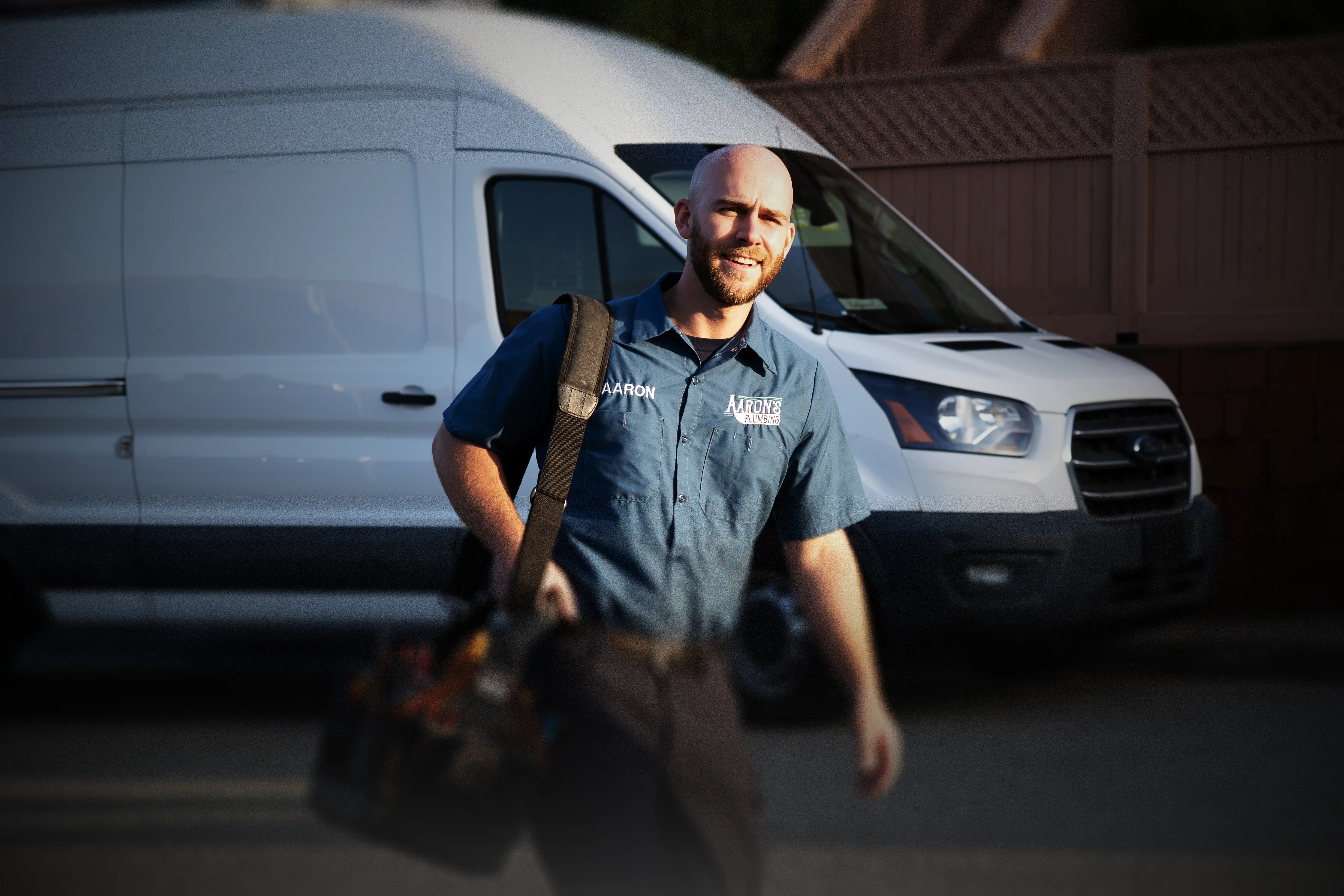 Licensed plumber Aaron Lindvall carrying professional tools next to a service van in Monterey County, CA