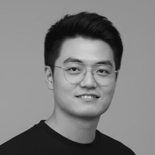 Portrait of a woman with long, smooth hair swept to the side, in a dark t-shirt, on a plain background.