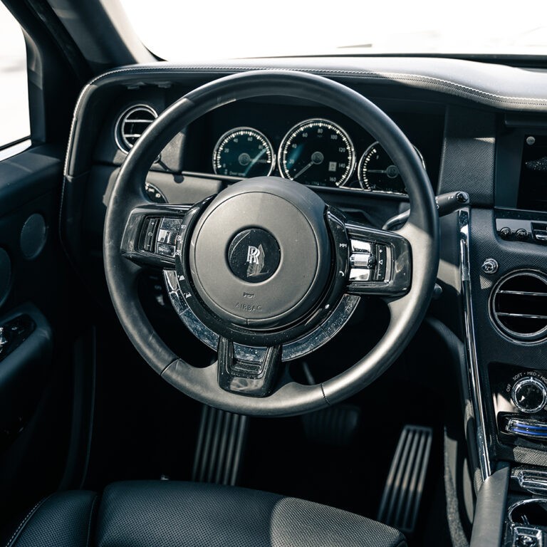 Interior view of the Rolls-Royce Cullinan's dashboard, highlighting the steering wheel and driver's controls.