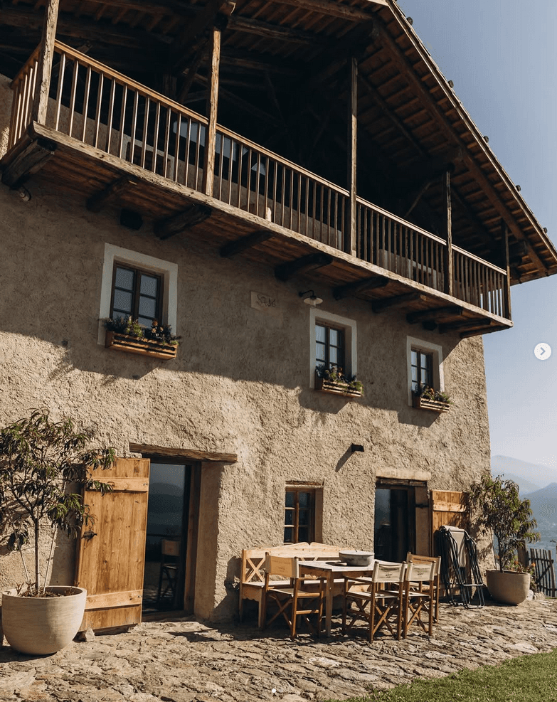 Terrace of a house in the Dolomites witha table and chairs out front.