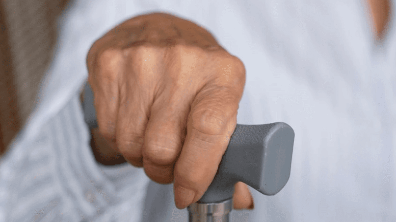 Mão de pessoa idosa segurando bengala