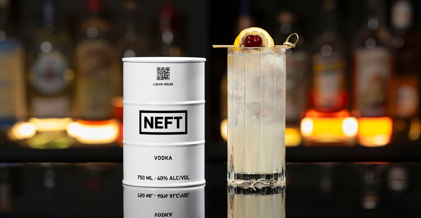 A NEFT Barrel and a glass of Vodka Collins on a bar counter.