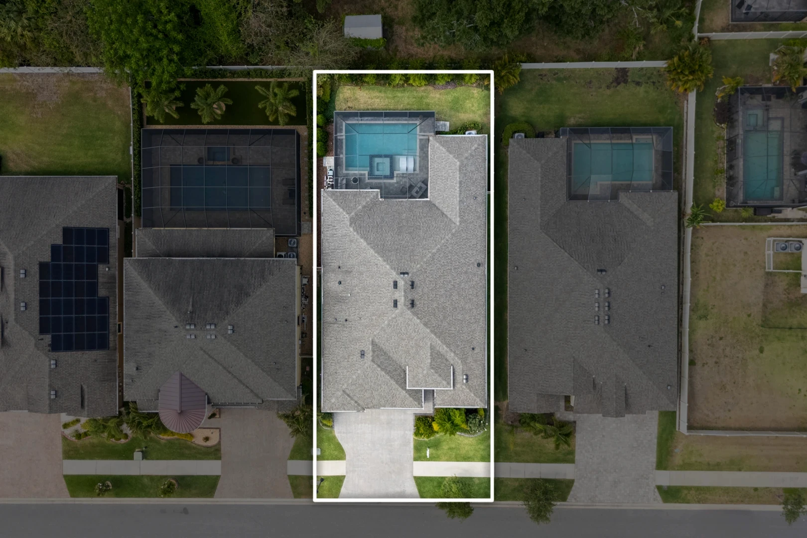 Aerial top-down view of a modern home with screened pool and an outlined property boundary