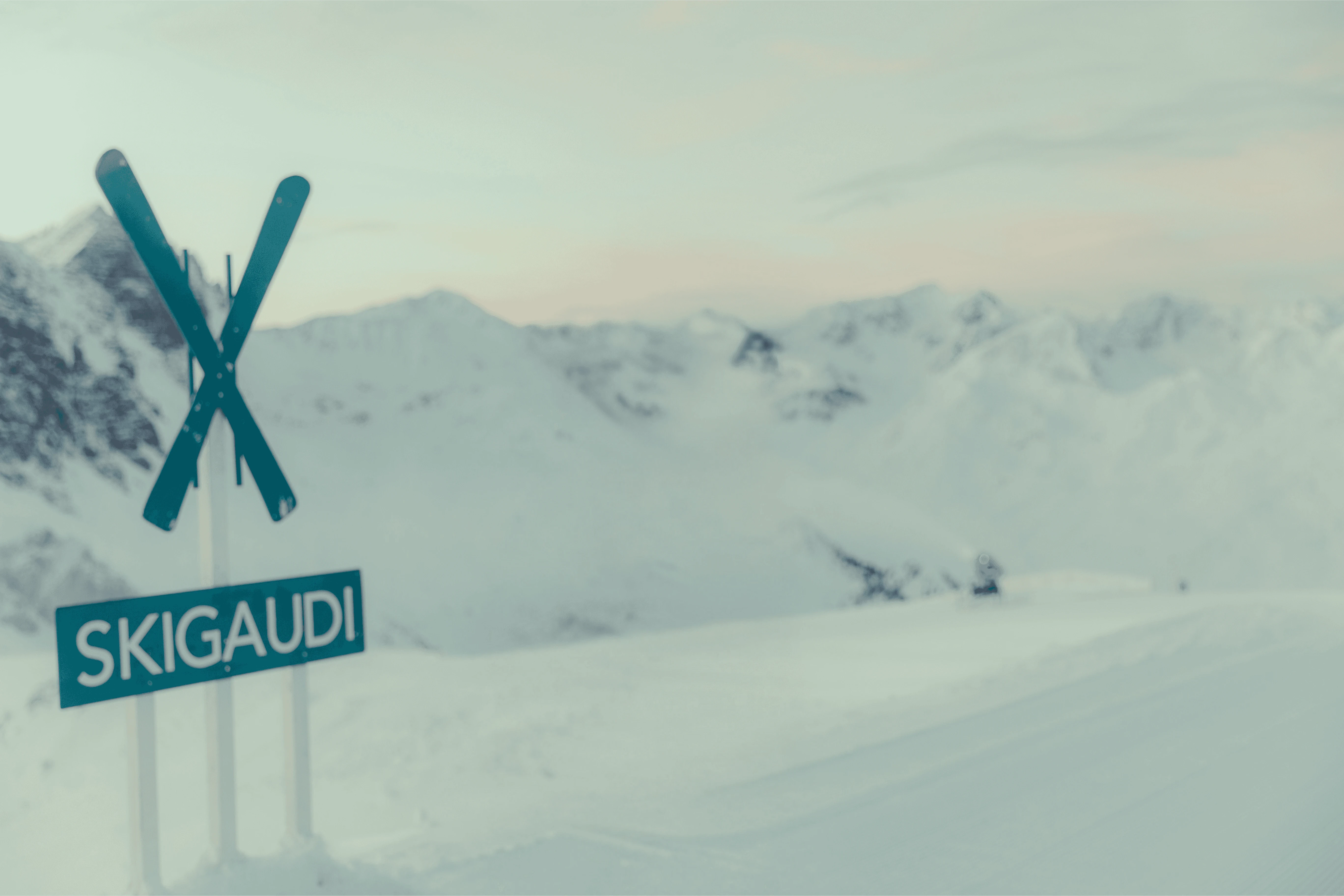 Ski resort sign with snowy mountain backdrop at sunset, promoting winter sports adventures.