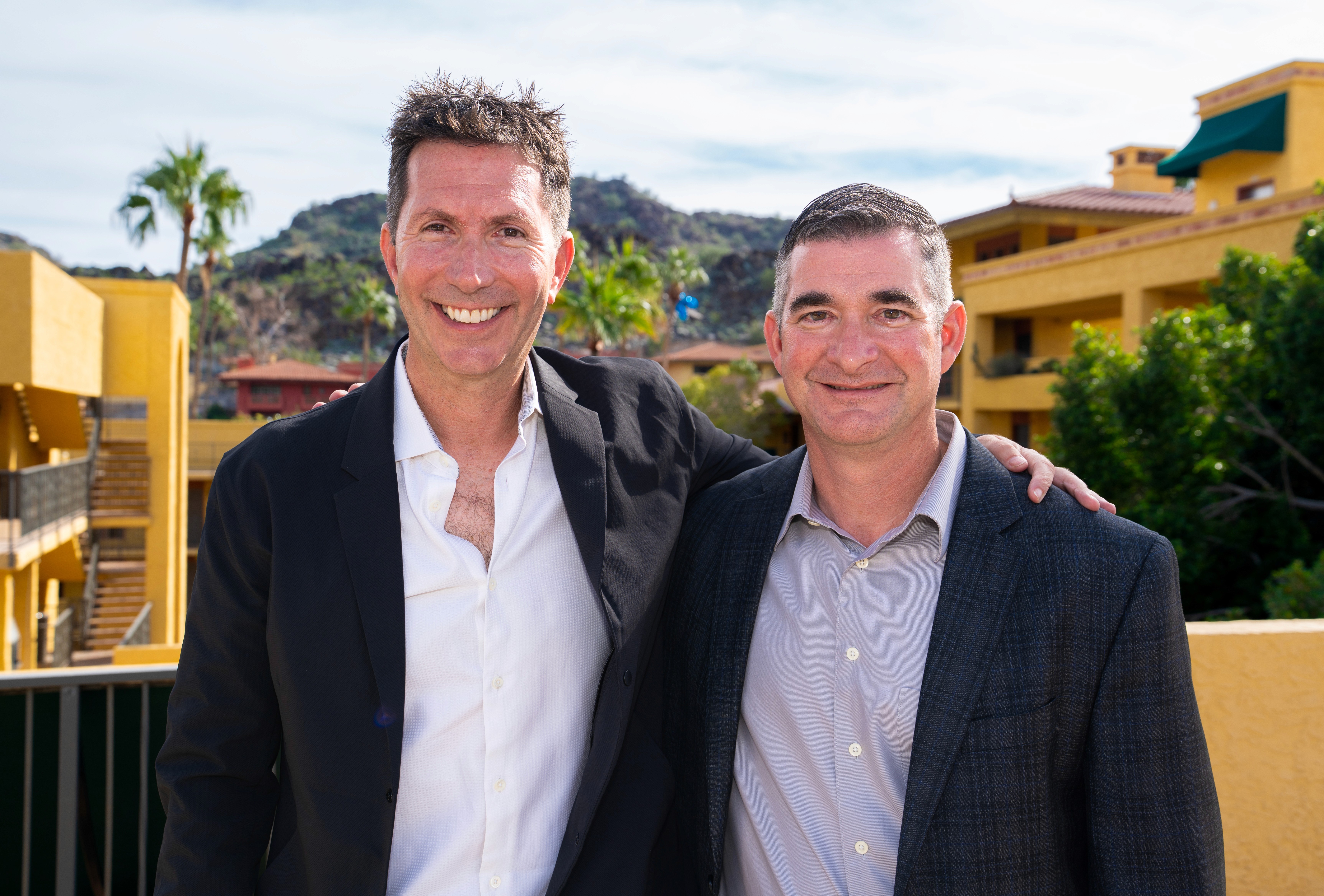 Man in glasses wearing a grey suit and blue tie, looking calmly at the camera.
